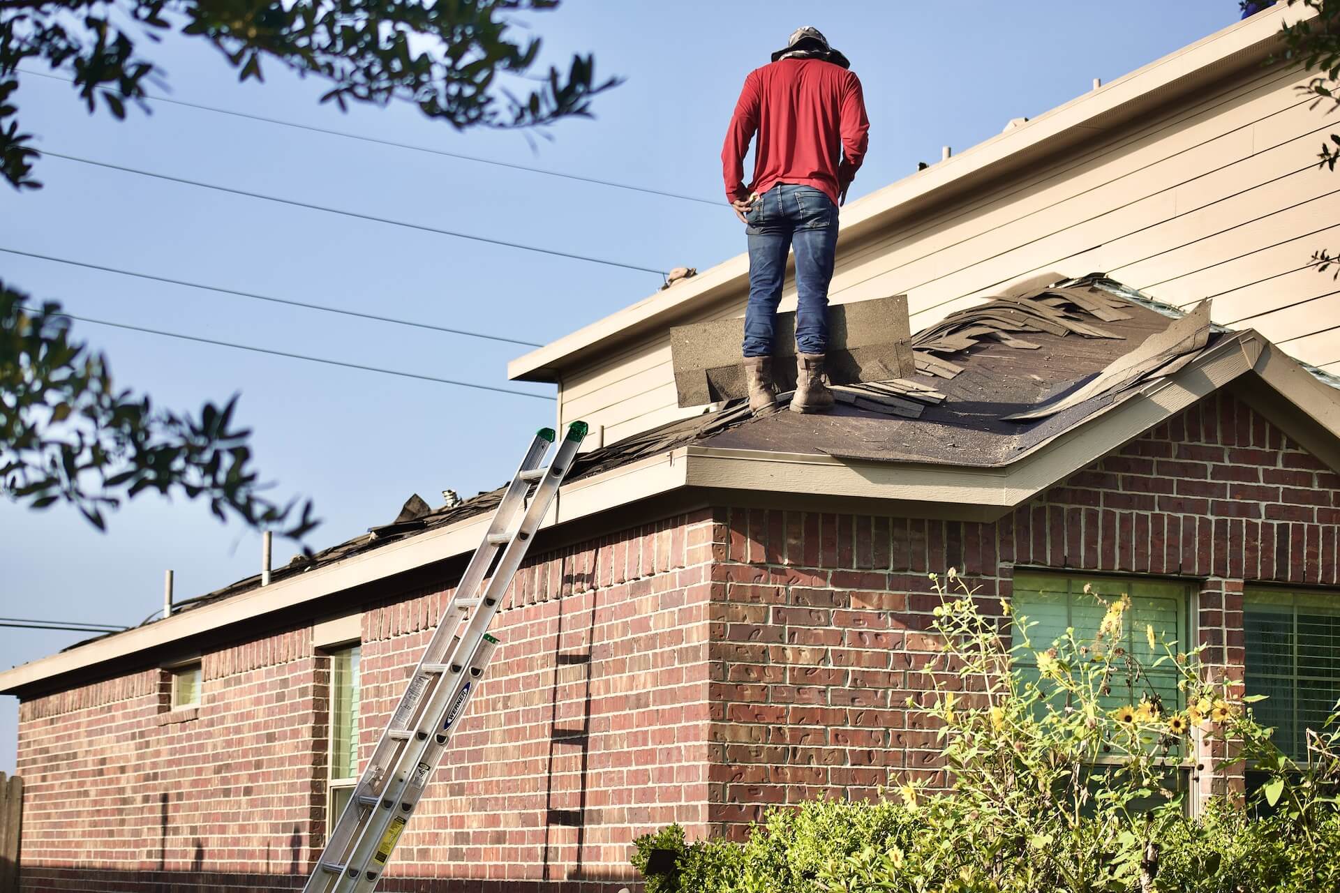 a picture of a man on a roof in Cincinnati determining if they should repair or replace the roof